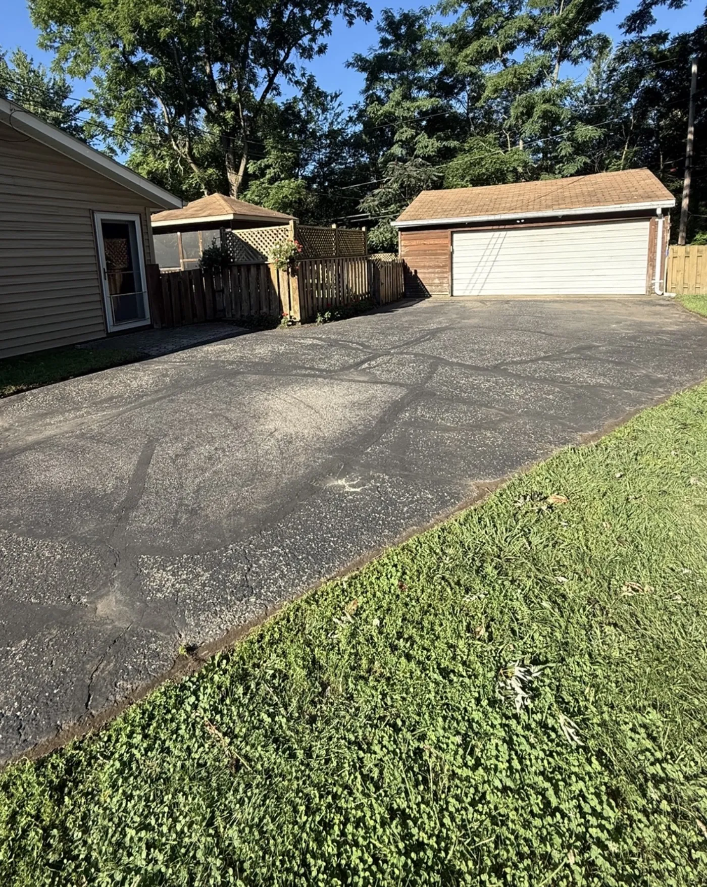Before: driveway sealcoating in Painesville, OH, cracked and weathered rear parking pad