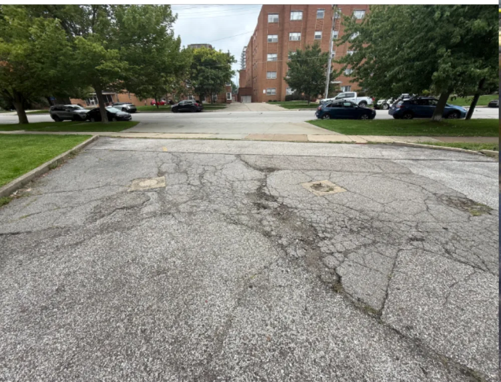 Before: street side entrance apron at a Mr. Tire shop in Lakewood, OH, patched and cracked asphalt at the sidewalk