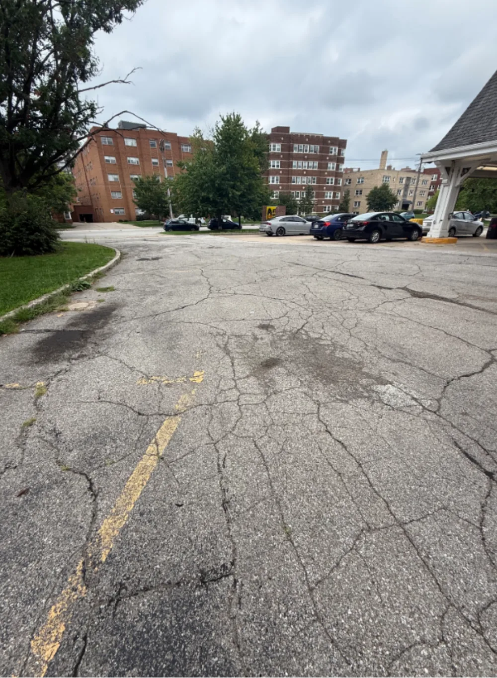 Before: main customer parking area at a Mr. Tire shop in Lakewood, OH, badly cracked gray asphalt with faded striping