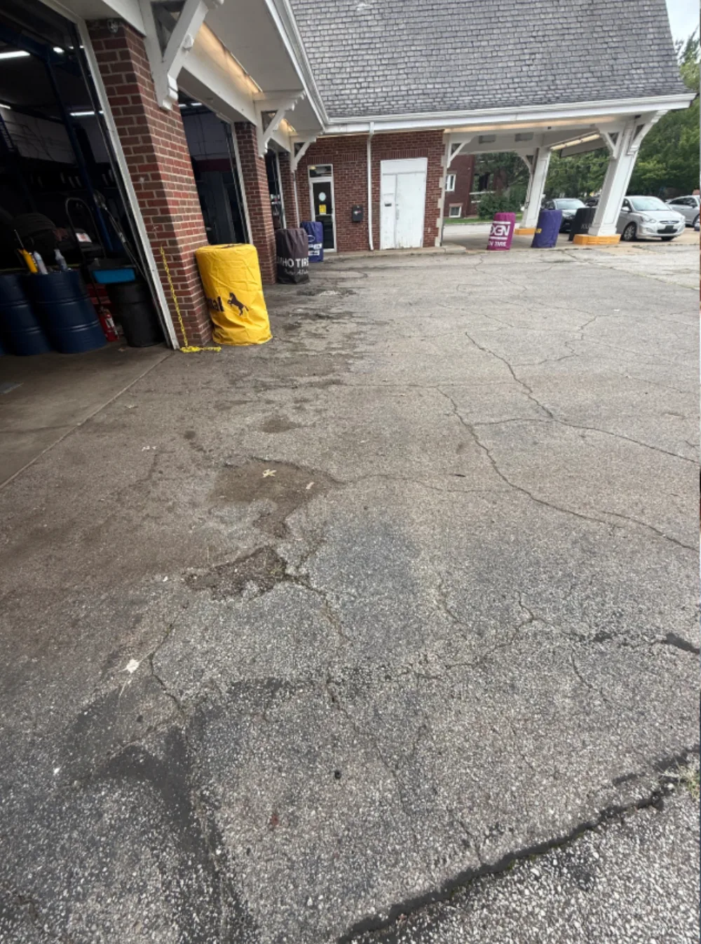 Before: pavement in front of the service bay doors at a Mr. Tire shop in Lakewood, OH, worn cracked asphalt