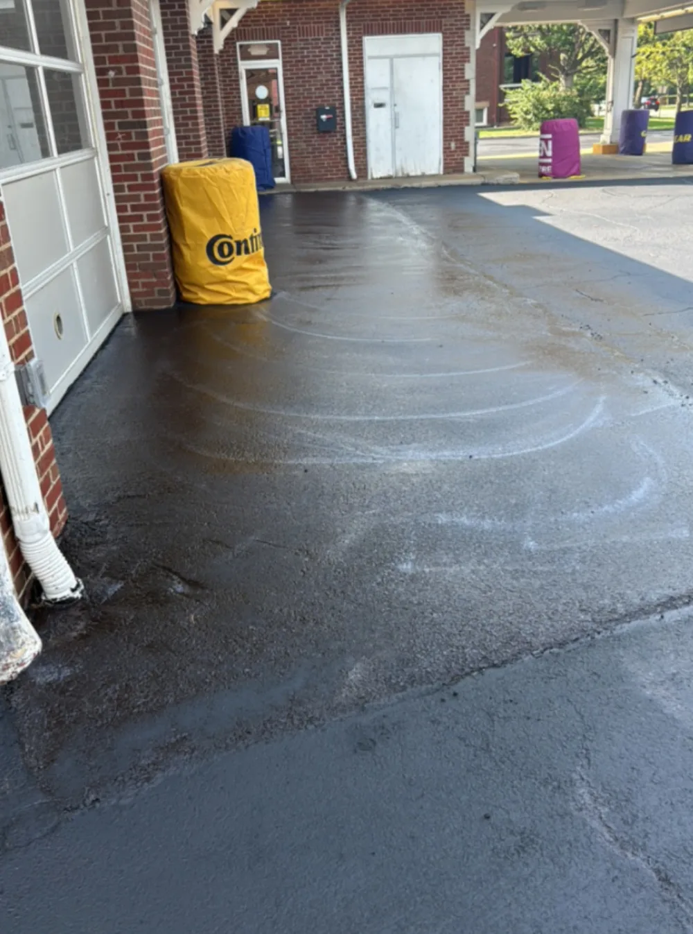 After: pavement in front of the service bay doors at a Mr. Tire shop in Lakewood, OH, deep black sealcoated asphalt by Rendon Paving