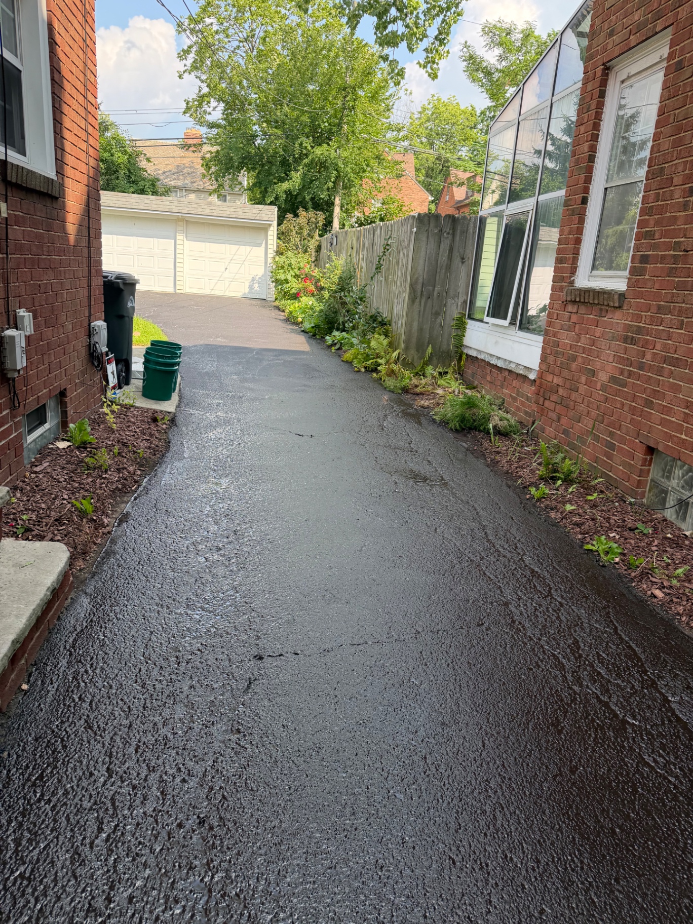 Freshly sealed asphalt driveway between two homes in Shaker Heights, Ohio