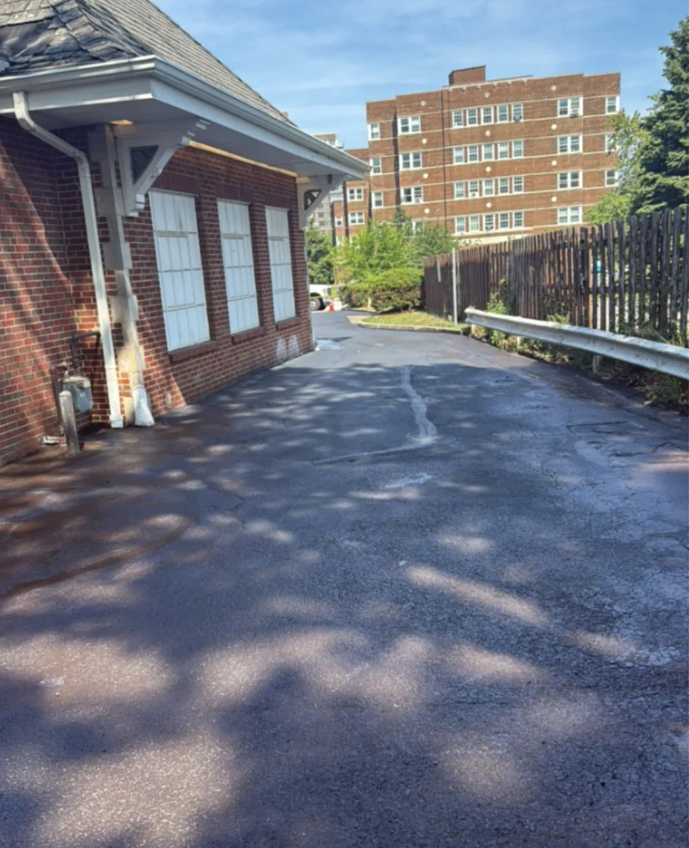 After: side service drive at a Mr. Tire shop in Lakewood, OH, cleaned and sealcoated black asphalt by Rendon Paving